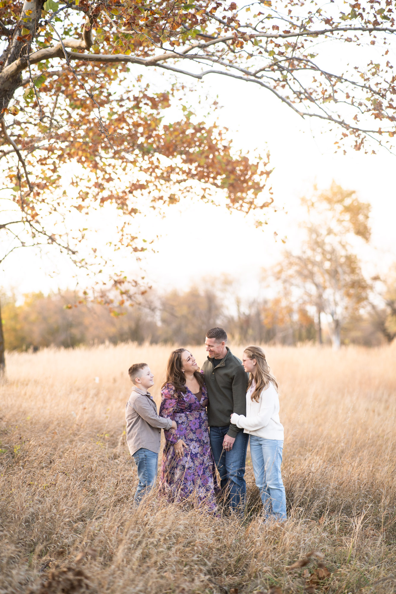 A family of four sharing a relaxed moment together in an autumn field