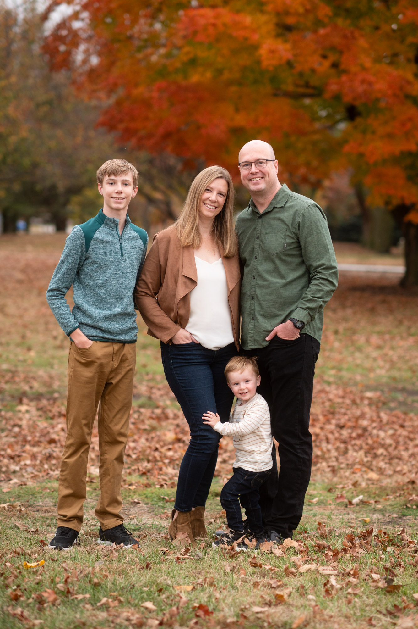 Sam standing with his family outdoors in autumn