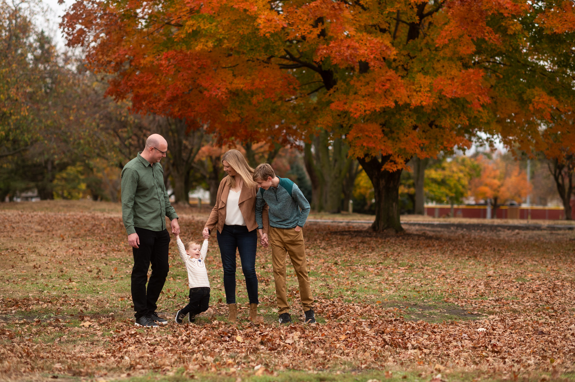 Sam walking with his family beneath autumn trees